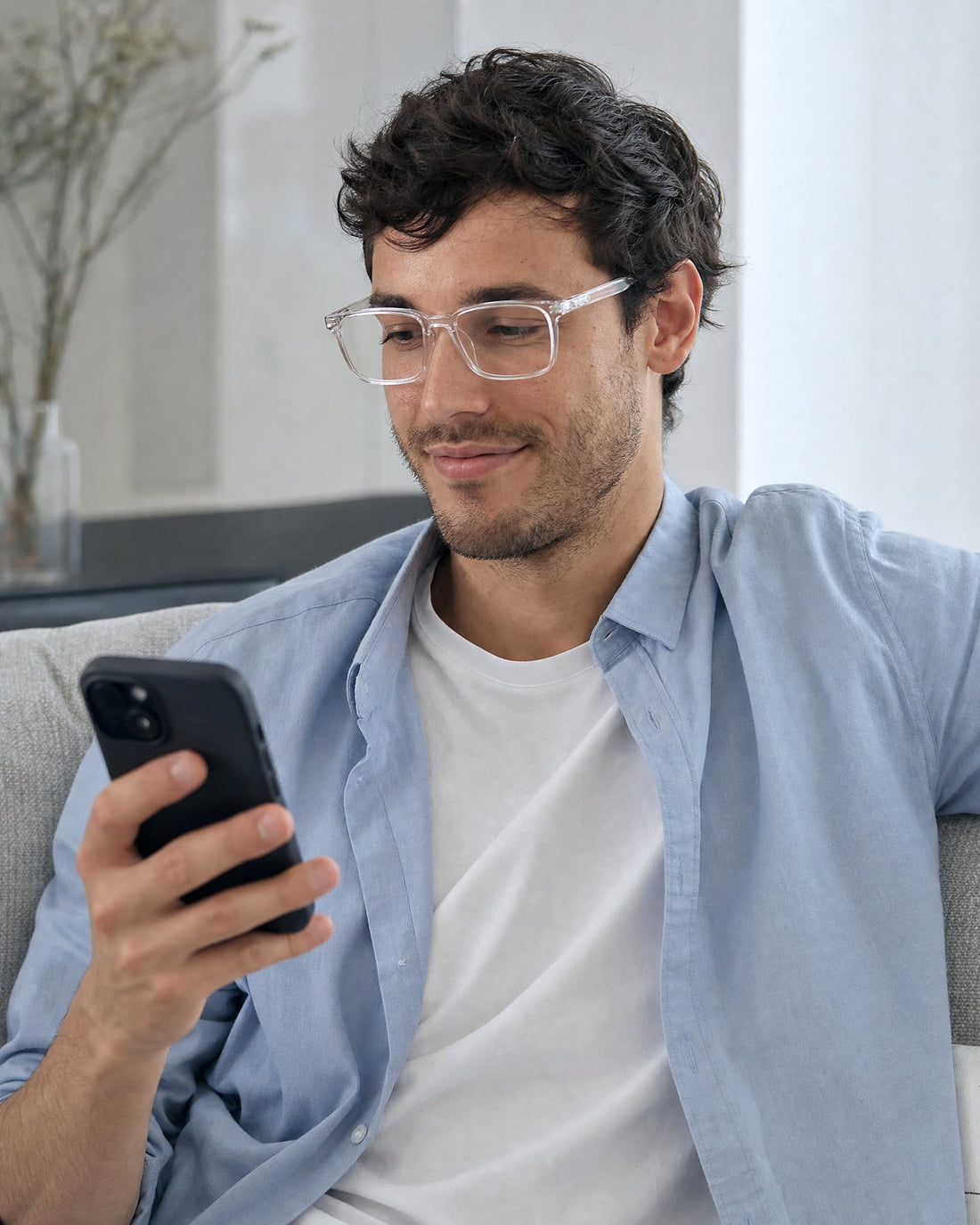 Chico con gafas de luz azul sin graduación transparentes mirando el móvil